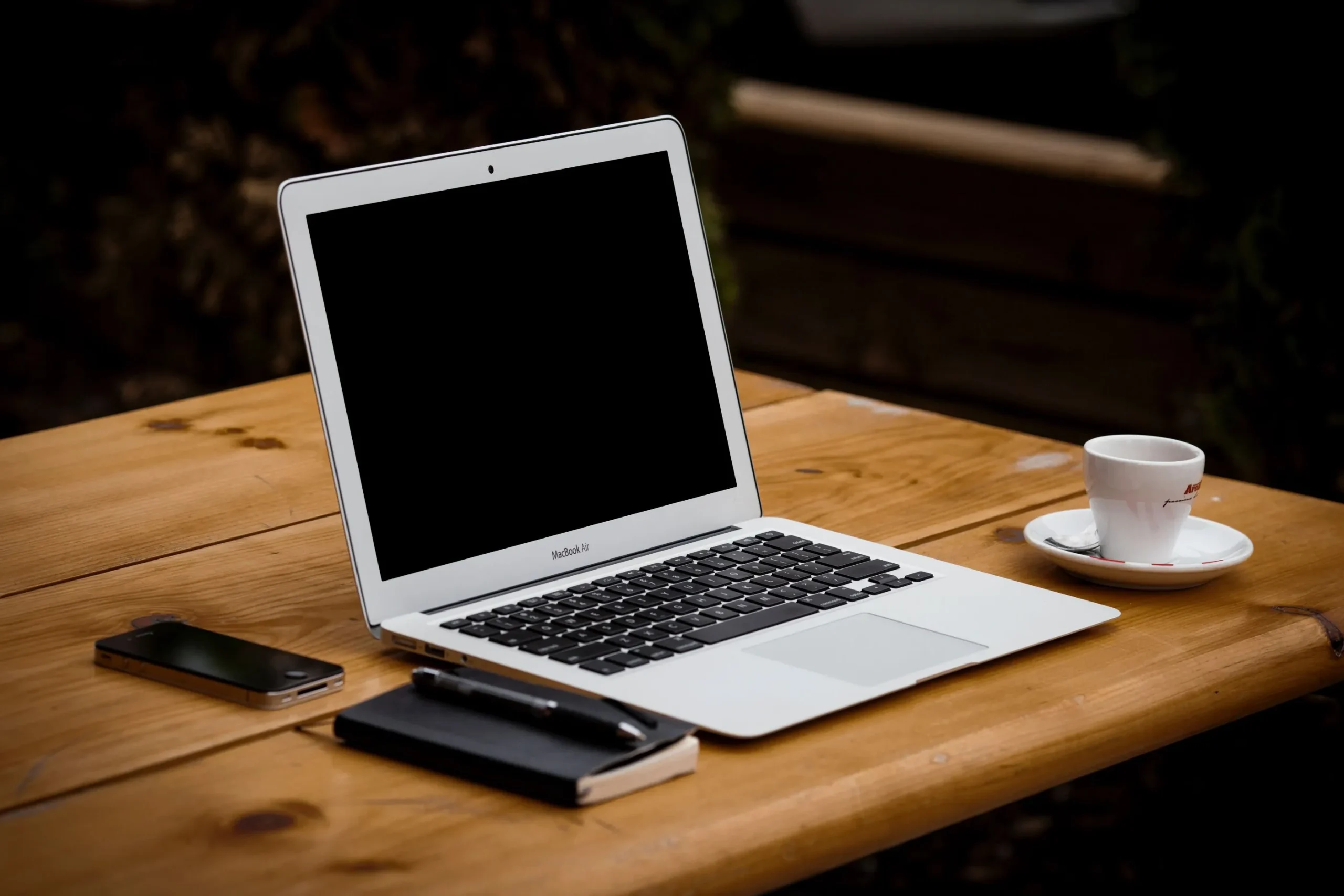 Image of laptop with phone, notebook, and coffee cup.